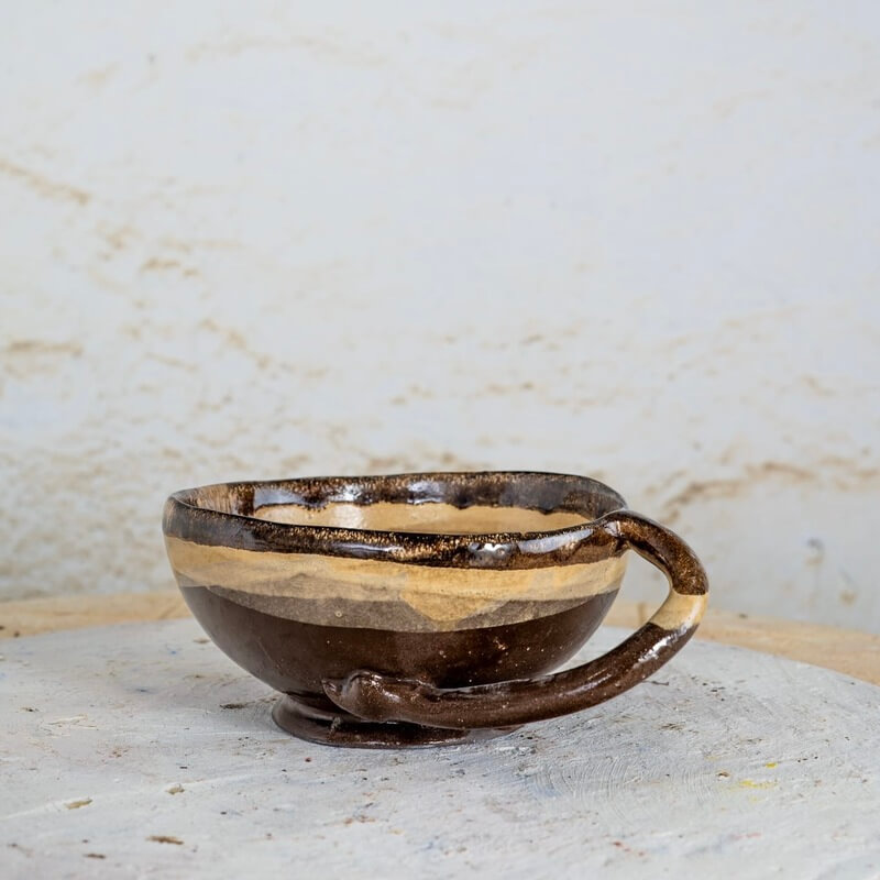 Keramična skleda iz temno rjave gline z ročajem v obliki zmajevega repa, peščena glazura in medeni rob, idealna za kosmiče in zimske juhice.