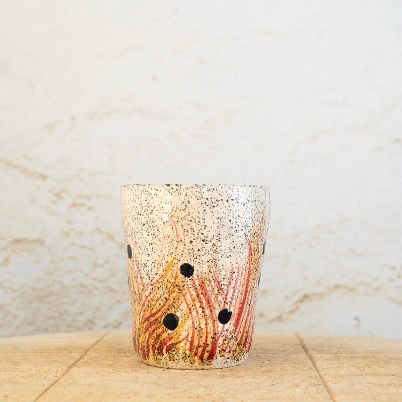 Ročno izdelan cvetlični lonec iz bele šamotne gline, dekoriran z ognjenimi potezami in črnimi pikami, ki simbolizirajo pepel v zraku.