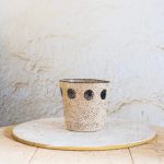 Ročno izdelan beli cvetlični lonec z drobnimi kamenčki in črnim vzorcem krogov, primeren za sodobne skandinavske interierje.