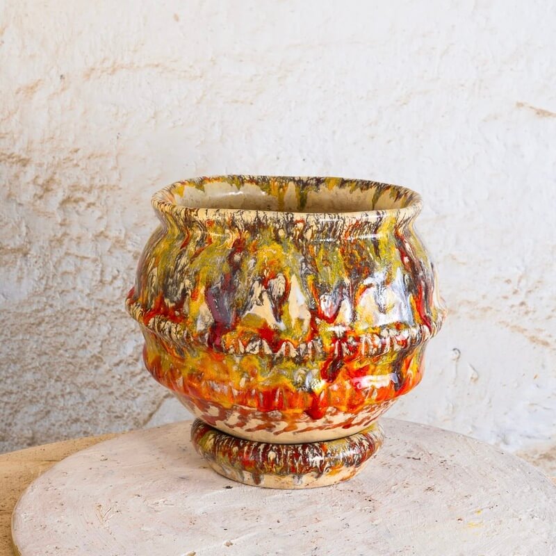 Ročno izdelan cvetlični lonec Ignis s podstavkom, narejen s tehniko kačic iz bele in terra cotta gline, z živahnimi prelivi glazur v ognjenih oranžnih, rumenih in rjavih tonih.