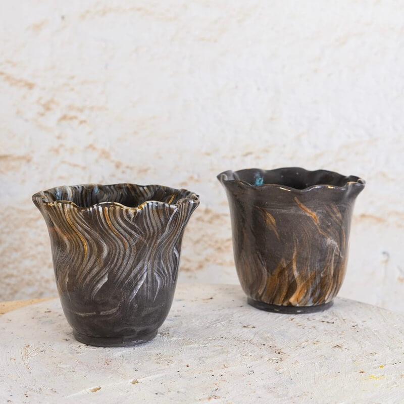 Ročno izdelana cvetlična lonca iz črne gline Nigra z valovitimi robovi, dekorirana z belo engobo in nežno pozlato.