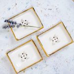 Minimalističen milnik Aurum s pozlačenim robom za pridih elegance vsakodnevnim ritualom. Sredinski gumbi in odtočne luknjice ohranjajo milo suho.