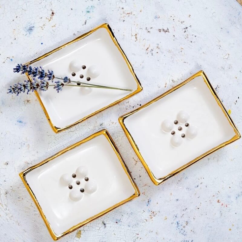 Minimalističen milnik Aurum s pozlačenim robom za pridih elegance vsakodnevnim ritualom. Sredinski gumbi in odtočne luknjice ohranjajo milo suho.