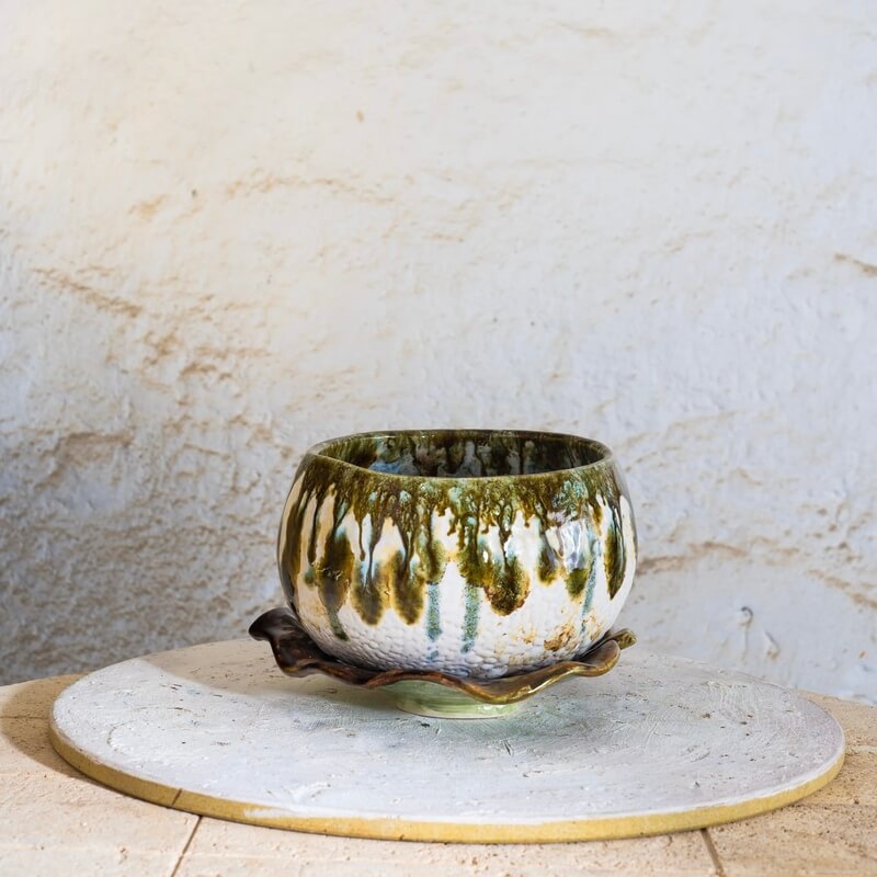 Ročno izdelan keramični lonec s podstavkom v obliki lista. Narejen s tehniko kačic, glaziran z belo craque in zeleno efekt glazuro. Z luknjicami za odtekanje vode – popoln za sukulente, zelišča ali rastline z dušo.