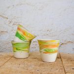 Skodelice brez ročaja iz vlivnega porcelana z marmornim vzorcem barvnih engob, idealne za kavo, čaj ali kakav.