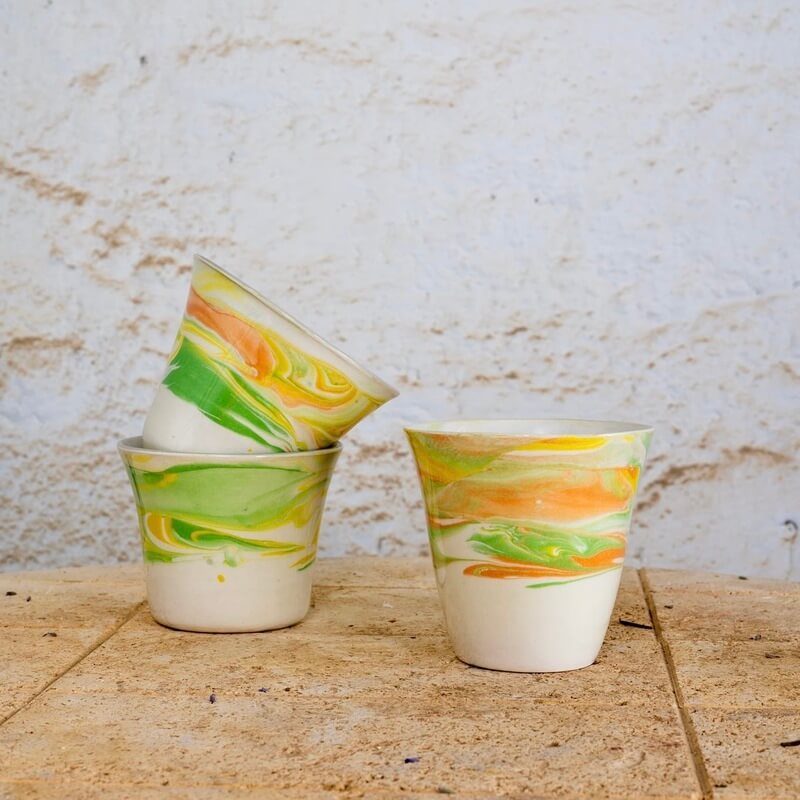 Skodelice brez ročaja iz vlivnega porcelana z marmornim vzorcem barvnih engob, idealne za kavo, čaj ali kakav.